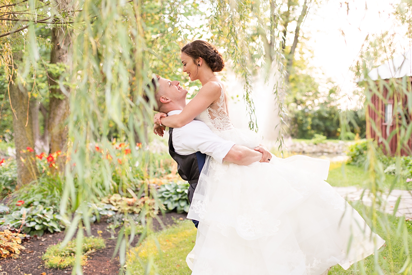 Groom lifting bride under a willow tree