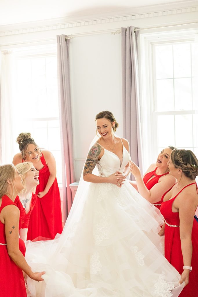 Bridesmaids helping bride get into her wedding dress