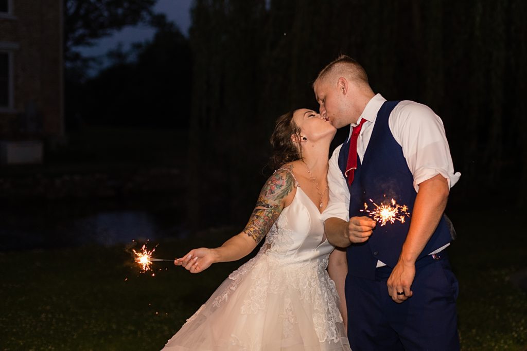 Bride and groom kissing while holding sparklers