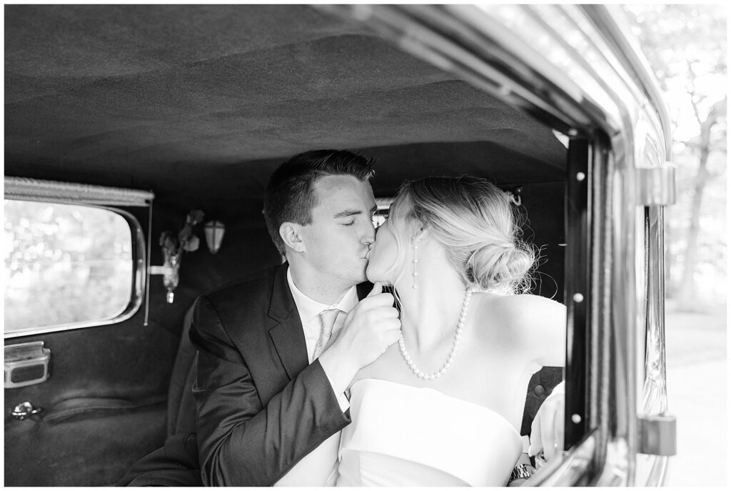 Bride and groom kissing in classic car