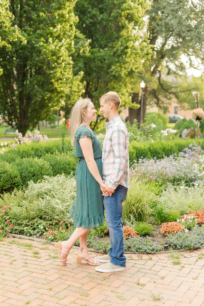 A couple is holding hands and looking at each other while taking their engagement photos at one of the best engagement session locations in Columbus - German Village