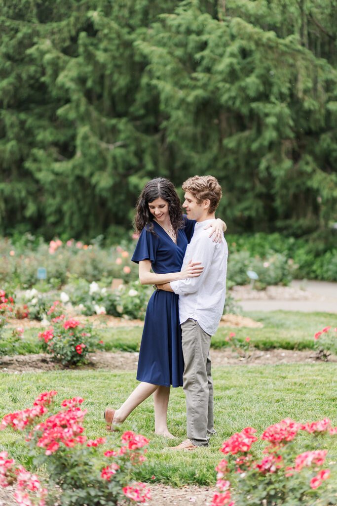 Columbus Park of Roses Engagement Photo – A couple walks hand in hand through vibrant rose gardens at the Columbus Park of Roses.